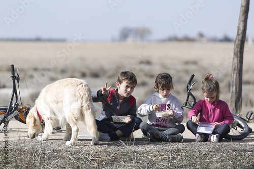 Three children sitting on floor taking outdoor snack