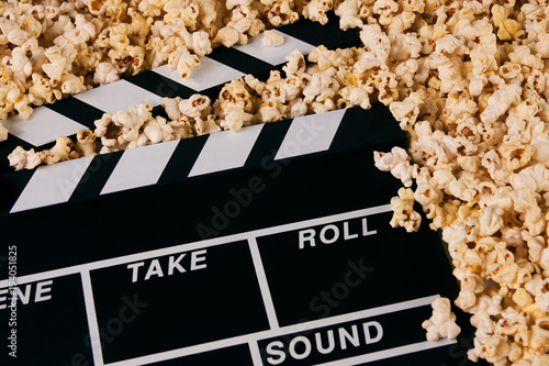 Clapper board and pop corn. Black wooden movie clapper with sweet popcorn, close-up. Movie time concept
