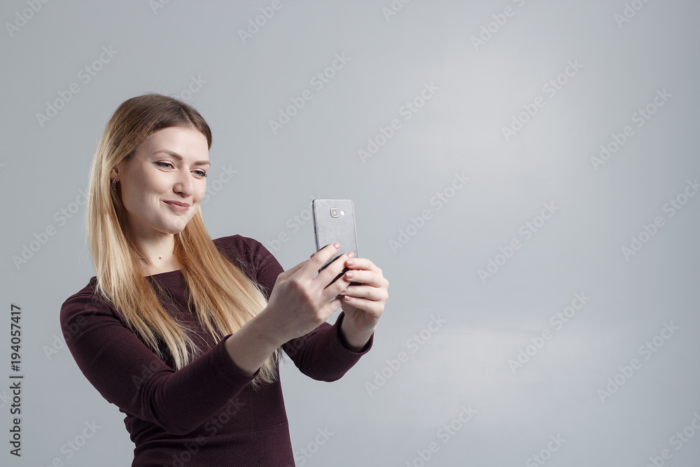 The girl makes selfie on the phone on a gray background, isolate The girl makes selfie on the phone on a gray background, isolate
