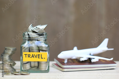 Saving planning for Travel budget of holiday concept,Financial,Stack of coins money in the glass bottle and airplane on passport with wooden background photo