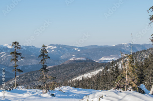 Winter landscape in the mountains with blue sky and snow-capped peaks and forest