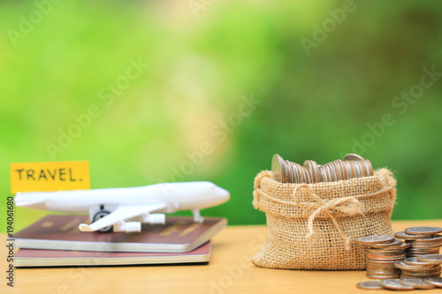 Saving planning for Travel budget of holiday concept,Financial,Stack of coins money in bag and airplane on passport with natural green background photo