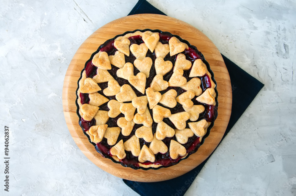 Cherry pie with heart shape decorations from flaky dough on a white backdrop Cherry pie with heart shape decorations from flaky dough on a white backdrop