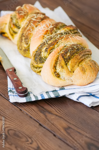 Italian pesto braided bread on a napkin, wooden background.