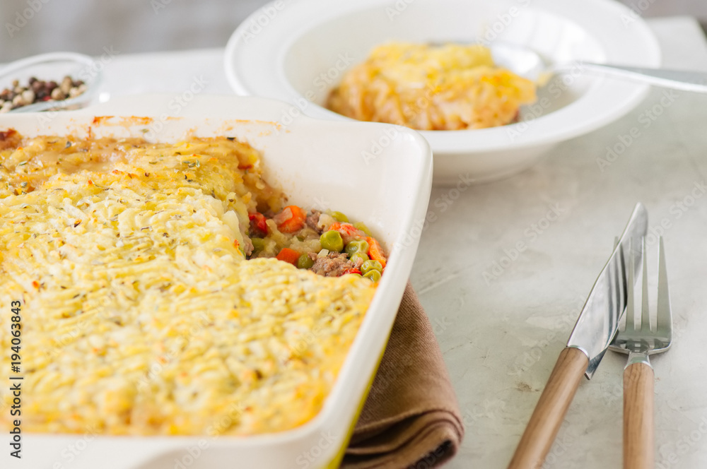 Shepherds pie - Irish traditional food. Served in a ceramic dish on a white stone background. Shepherds pie - Irish traditional food. Served in a ceramic dish on a white stone background.