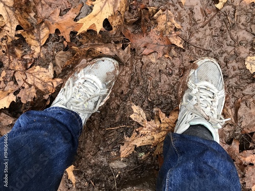 weibliche Sportschuhe in matschigem Waldboden