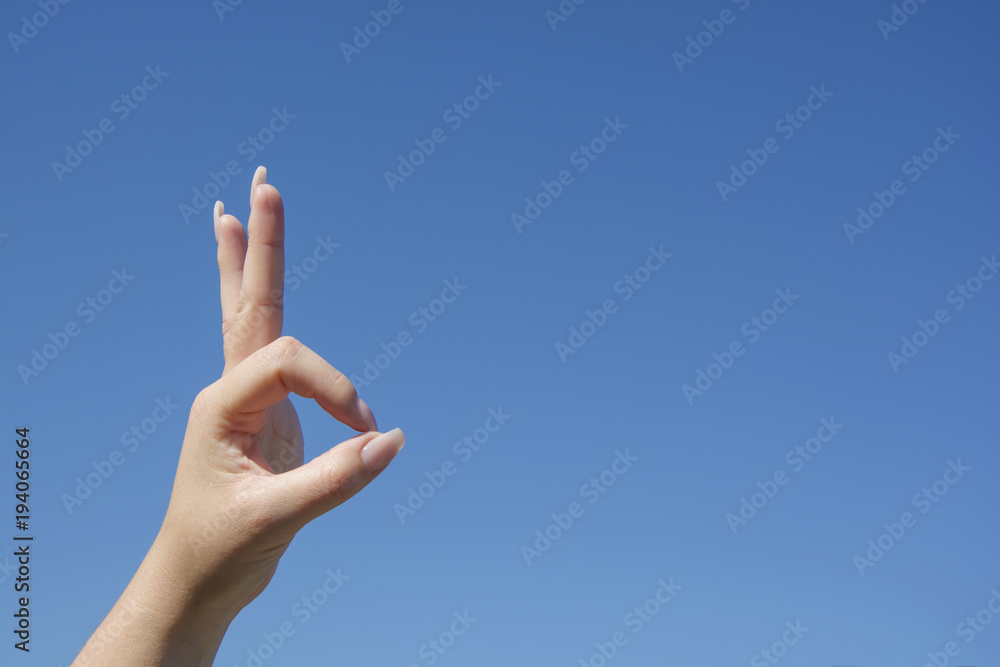 Woman hand show O.K. sign on blue sky background, symbol language body Woman hand show O.K. sign on blue sky background, symbol language body