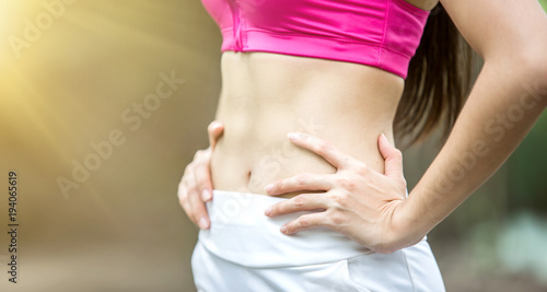 Close up shot of sport woman with her six pack muscle in sportswear outdoors at the park