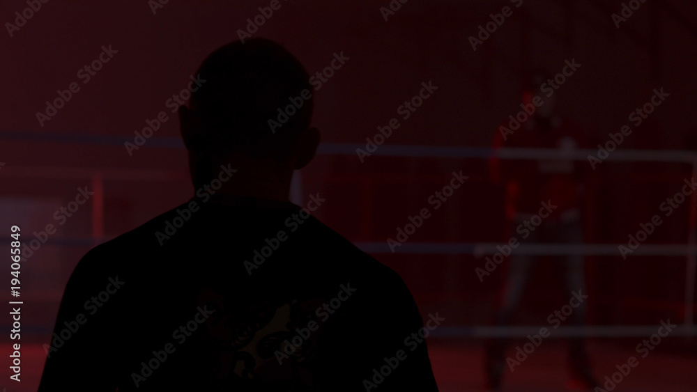 Silhouette of a man who comes into the room with a red light, back view. Shadow of man in the red room. Silhouette of a man in the light