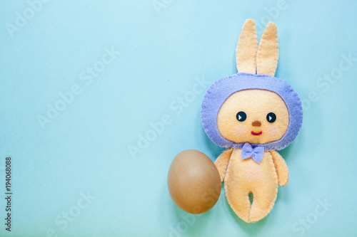 Easter rabbittoy with one brown egg is on blue background. photo