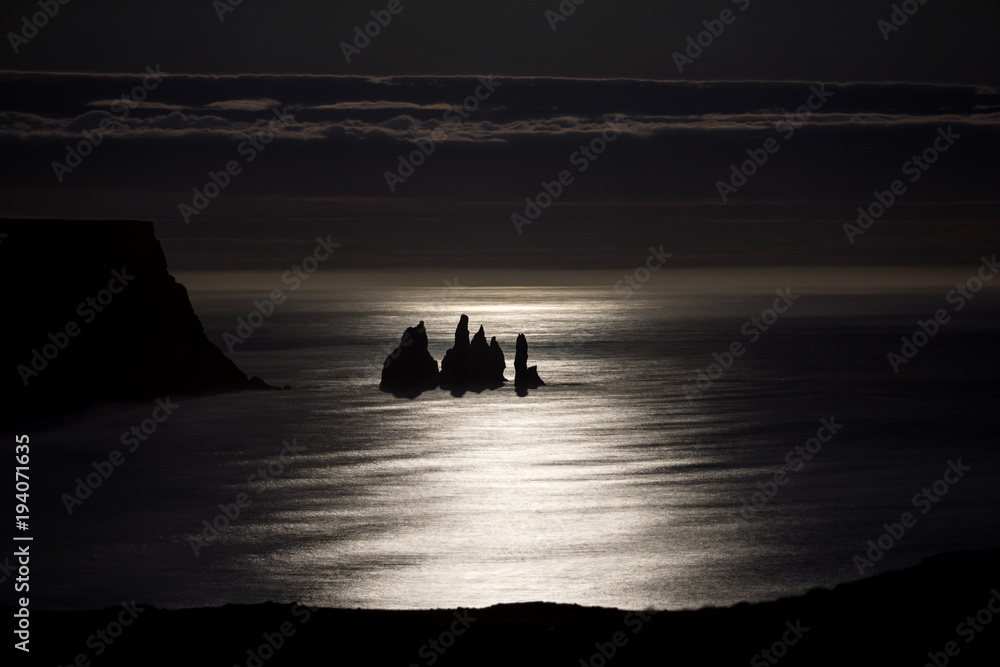 Moonshine illuminates the distinctive rock formations on Reynisfjara Beach in Iceland