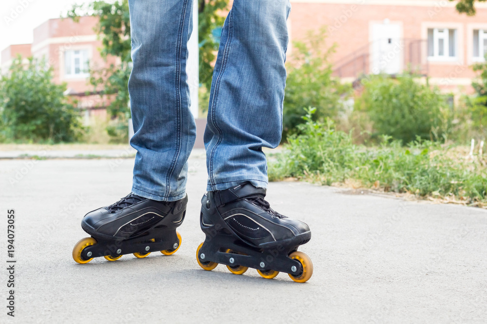 Young man in blue jeans riding roller skates in the city. Close up legs