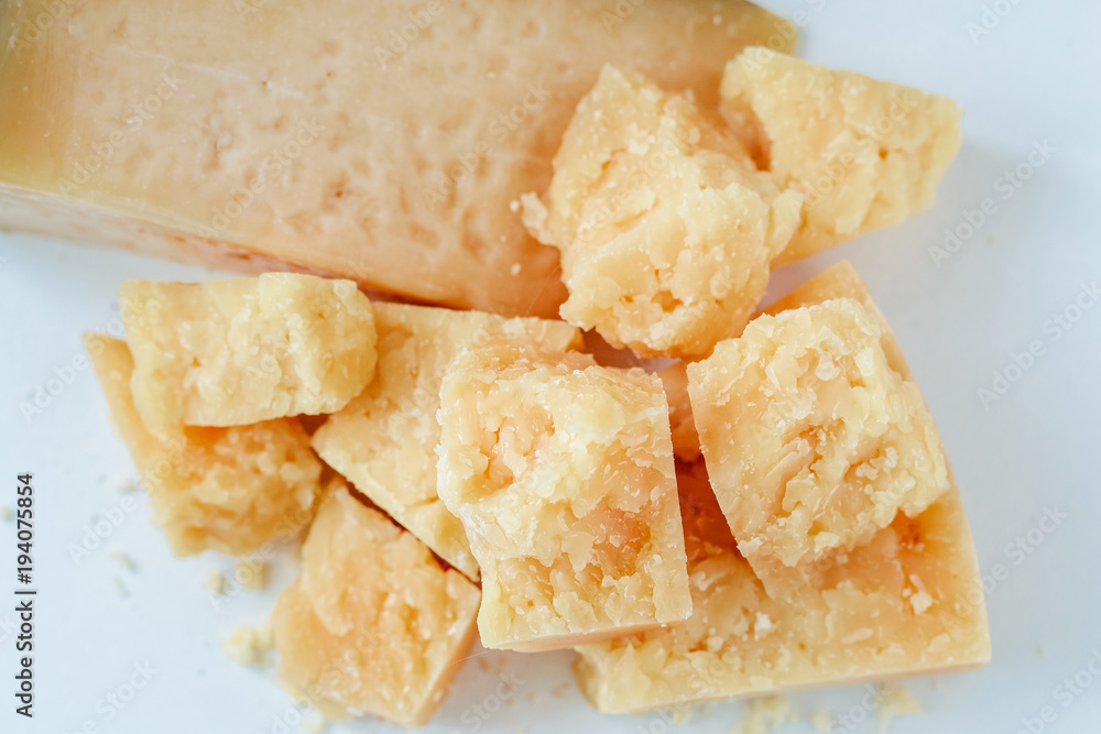 pile of pieces of parmesan cheese on a white background pile of pieces of parmesan cheese on a white background