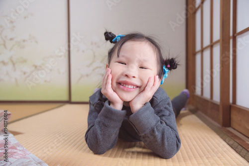 Little japanese girl lying on the floor and smile at camera