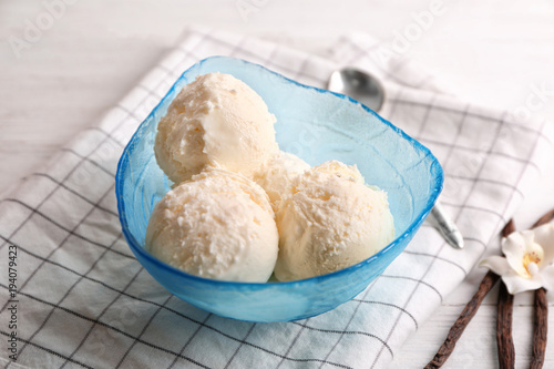 Bowl with delicious vanilla ice cream on table