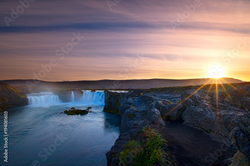 Godafoss Falls  Iceland with a sunburst and colors in the sky starting to turn at sunset with a long exposure of the falls 