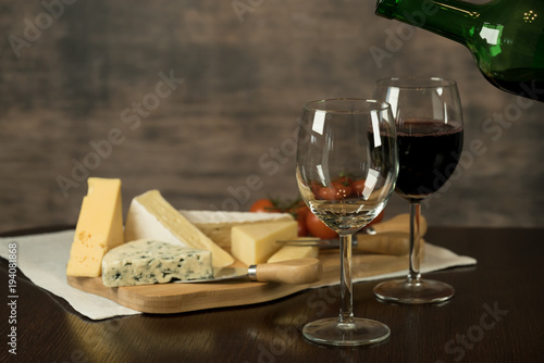 Red wine poured into a glass with cheese board 