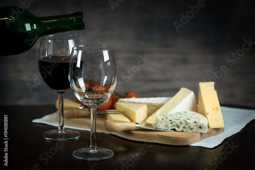 Red wine poured into a glass  with cheese board 