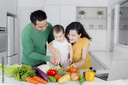 Happy asian woman cut vegetables with daughter and husband