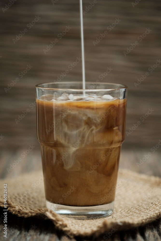 Classic still life with The hand is pouring milk to a glass of coffee, vertical vintage picture. Classic still life with The hand is pouring milk to a glass of coffee, vertical vintage picture.