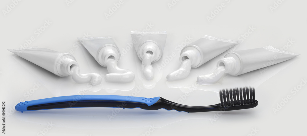 Five white tube with white toothpaste and black toothbrush Five white tube with white toothpaste and black toothbrush