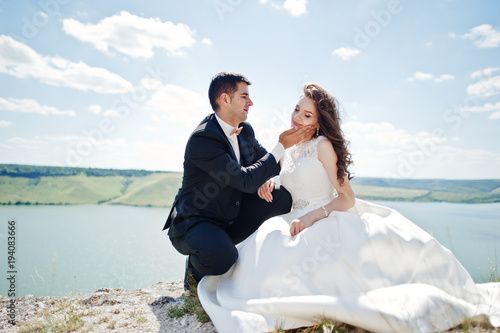 Wedding couple at breathtaking landscape with rock and lake.