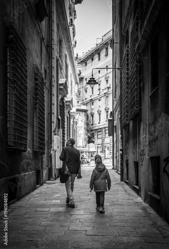 Father with little son walking by the narrow old Italian streets in Genoa, Italy.