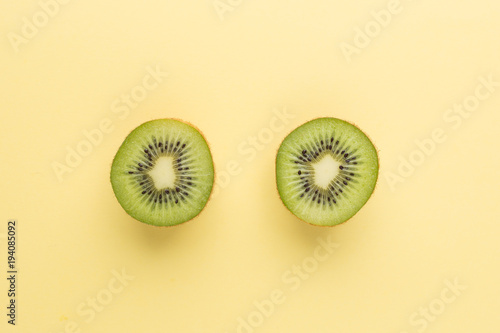 The concept of healthy eating. Half-cut kiwi on a pastel yellow background. Top View.