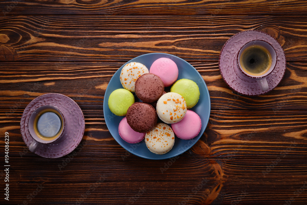 Cake macaron or macaroon with coffee on a wooden background. Space for text or design. Cake macaron or macaroon with coffee on a wooden background. Space for text or design.