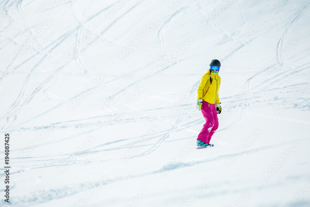 Photo of woman wearing helmet in sports clothes snowboarding