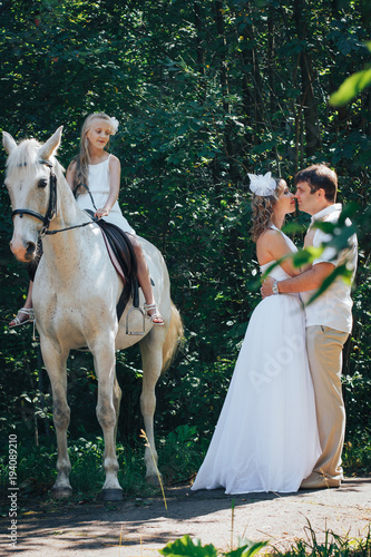 Man, woman dressed as a bride, girl and white horse in the park © keleny