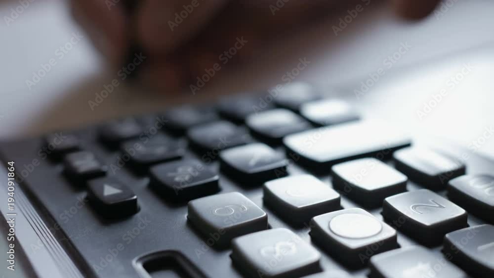 Man accountant hand holding pen counting on calculator. Businessman Doing Calculations Man accountant hand holding pen counting on calculator. Businessman Doing Calculations