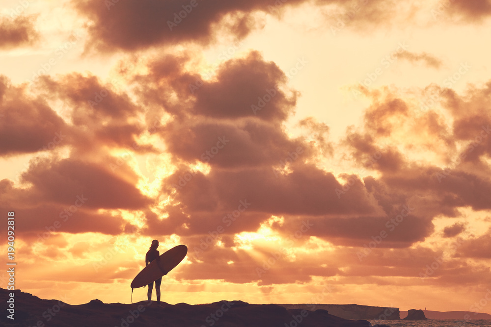 Surfer girl silhouette on sunset