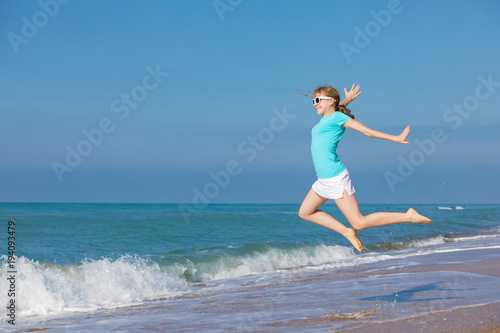 teen girl jumping on the beach at blue sea shore in summer vacation at the day time