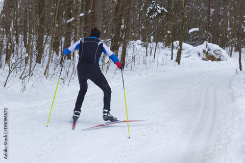 a man skier skating in a winter forest near trees