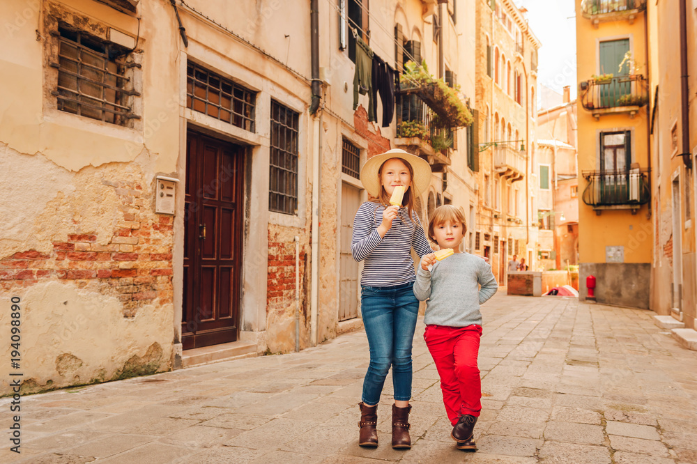 Two funny kids walking through old italian streets, family tavel with children. Kids eating ice cream