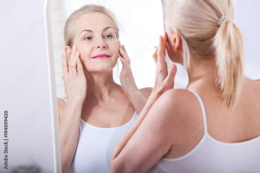 Forty years old woman looking at wrinkles in mirror. Plastic surgery and collagen injections. Makeup. Macro face. Selective focus Forty years old woman looking at wrinkles in mirror. Plastic surgery and collagen injections. Makeup. Macro face. Selective focus