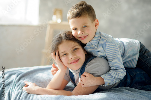 Two children, the boy and the girl, lie on a bed. photo