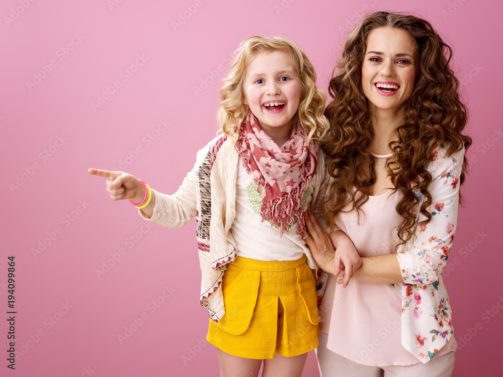 smiling mother and child isolated on pink pointing at something smiling mother and child isolated on pink pointing at something