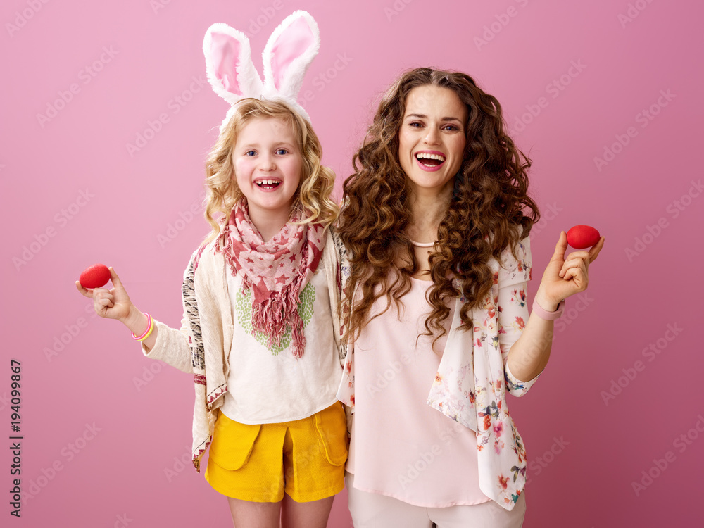 mother and daughter on pink background with red Easter eggs mother and daughter on pink background with red Easter eggs