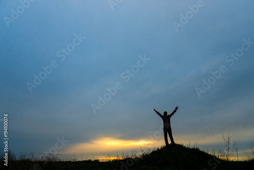 Man on the hill raise hands up to the sky. silhouette