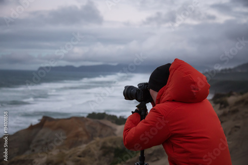 Photographer taking picture of the beautiful seascape on Pacific Ocean Coast. Taken in Cape Kiwanda, Oregon, America