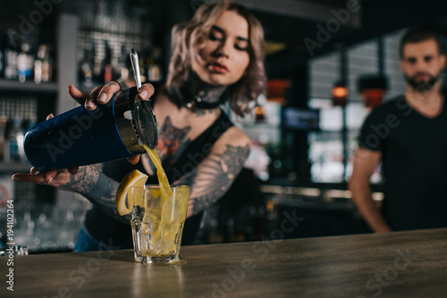 Obraz na plátně tattooed bartender preparing drink at bar