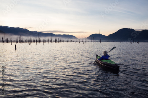 Adventurous Girl kayaking in a beautiful lake during a vibrant sunrise. Taken in Stave Lake, East of Vancouver, BC, Canada. © edb3_16