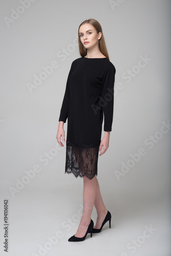 Young beautiful long-haired female model poses in black dress