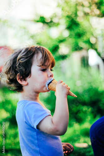 child eats ice cream on a summer day in the shade of a tree