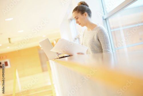 Student girl in school hall connected with laptop