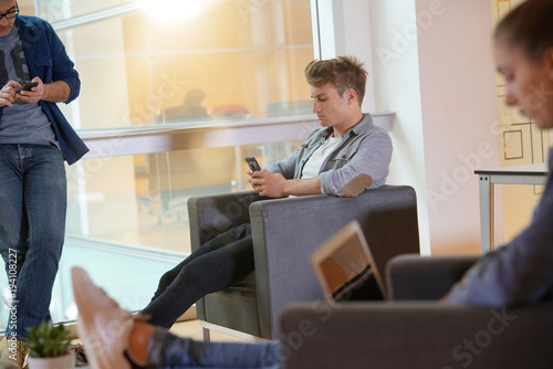 Young people relaxing in lounge room, connected