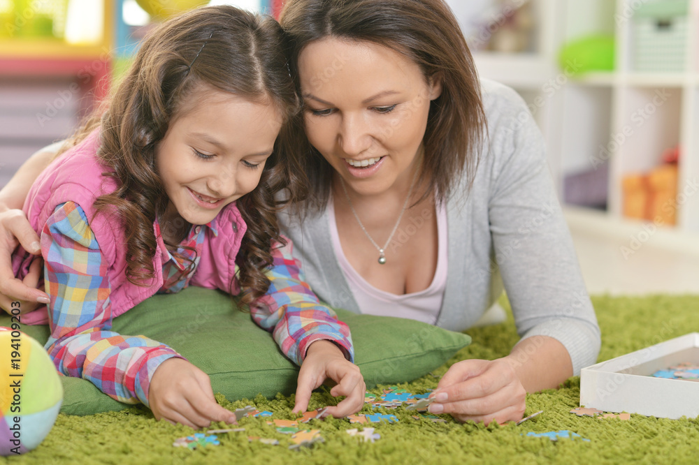 Mother with little daughter collecting puzzle Mother with little daughter collecting puzzle