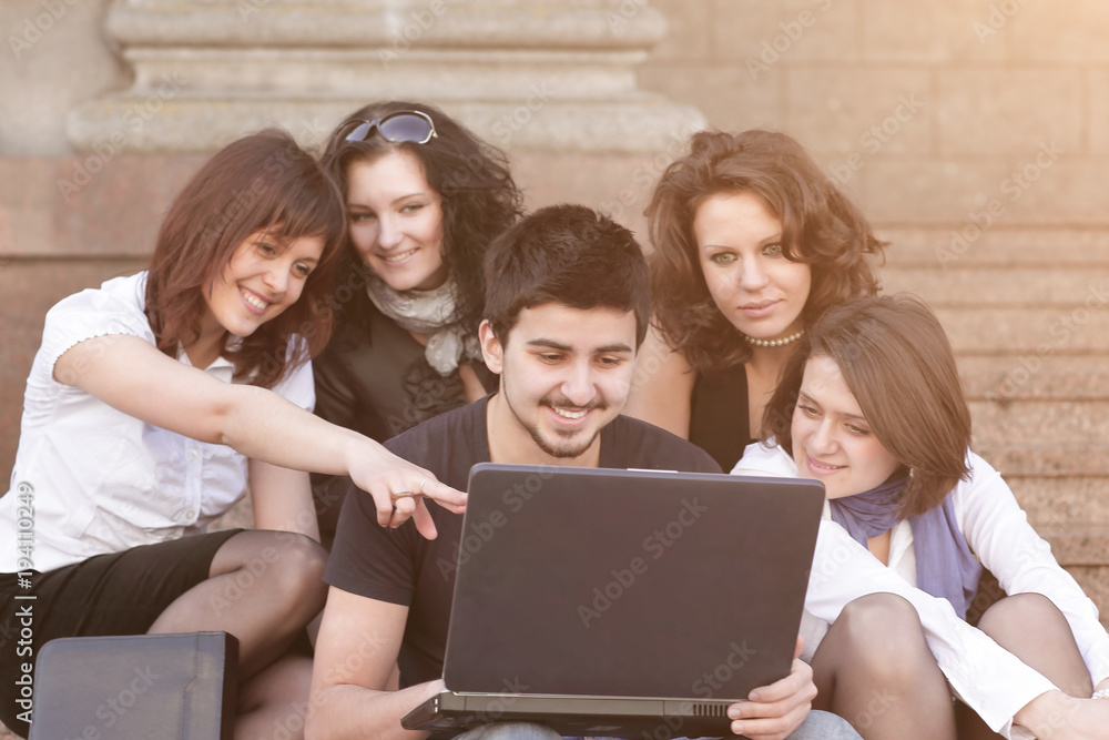 group of students discussing the information with the laptop. group of students discussing the information with the laptop.